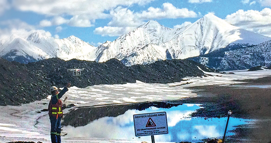A worker operates a drone near a toxic hazard area in a snowy mountainous landscape.